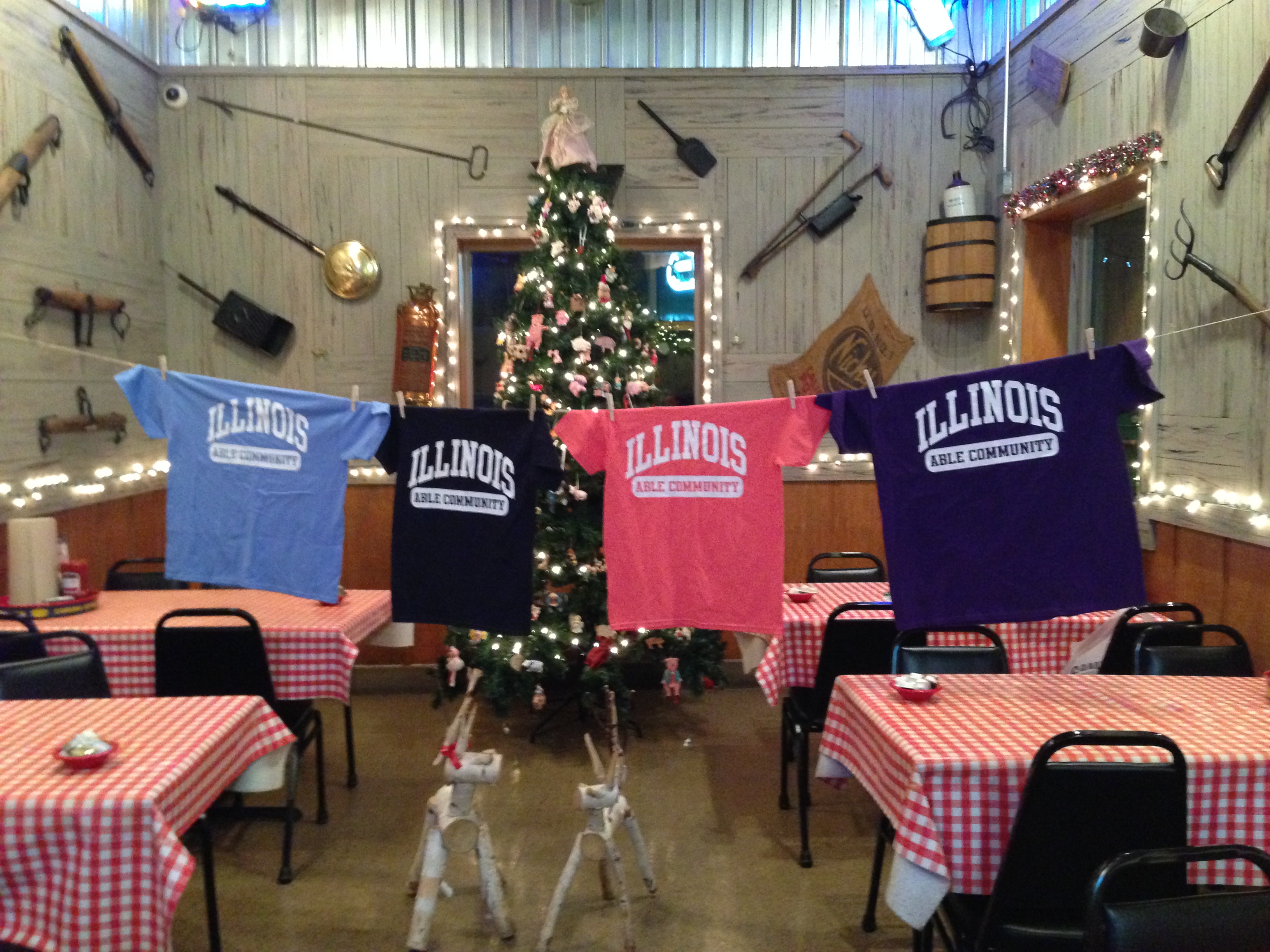 Able Community T-shirts strung in front of Uncle Bub's Christmas tree